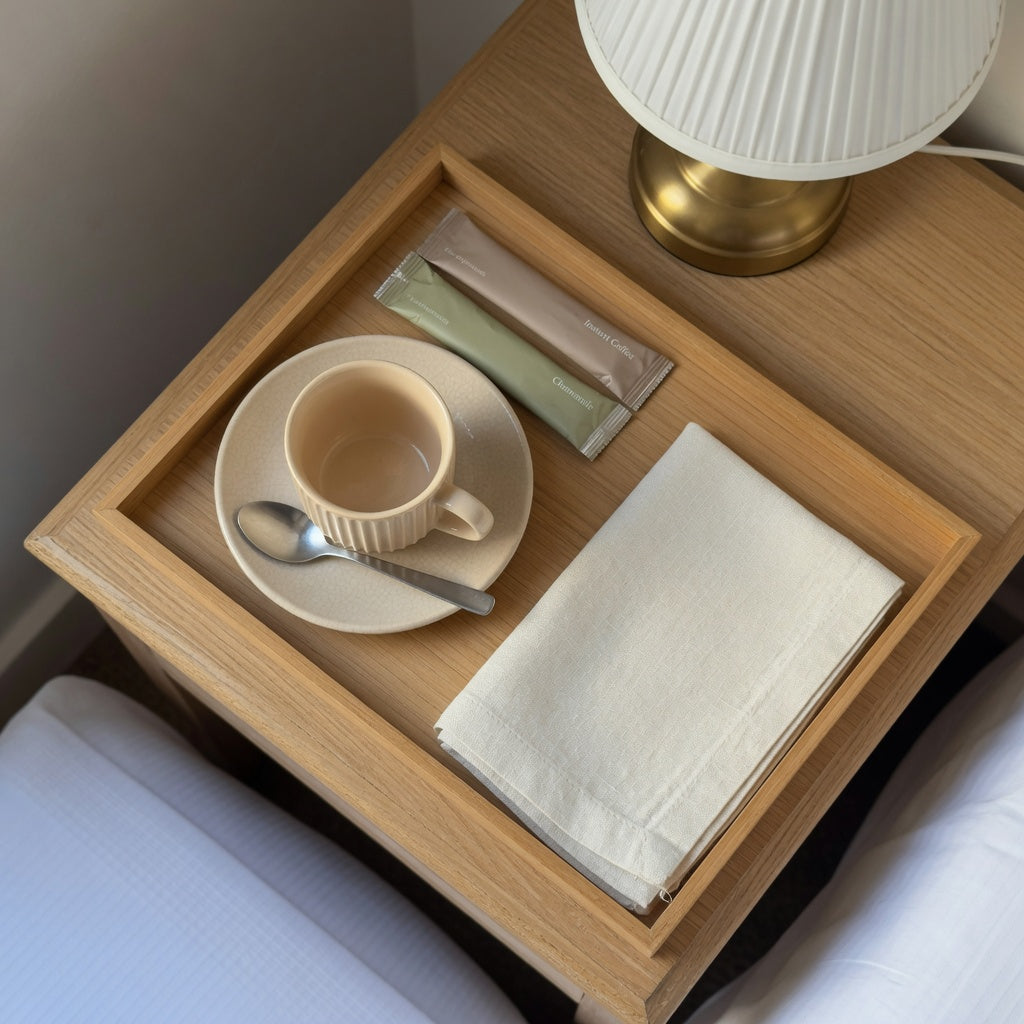 ceramic cup coffee tray guest room layout with a pleated cup, saucer, spoon, sachets, and clear nightstand space