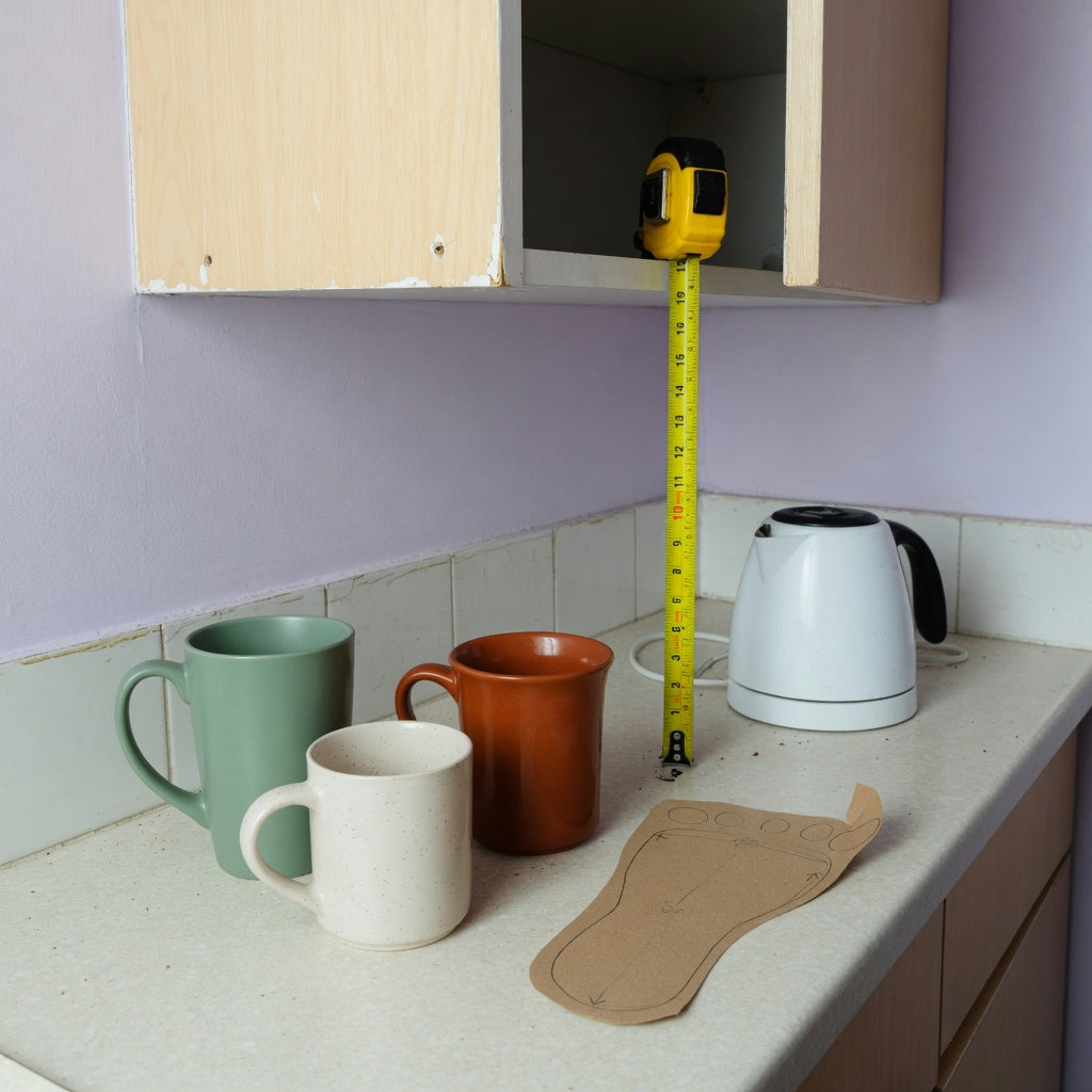 Ceramic tea mug compact kitchen practical purchase checklist with mugs, a tape measure, a narrow counter, and an open cabinet