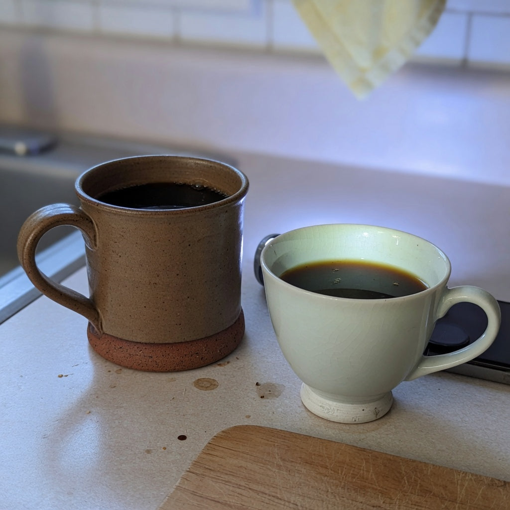 Thick stoneware mug and thinner porcelain cup showing ceramic vs porcelain coffee mugs differences on a kitchen counter