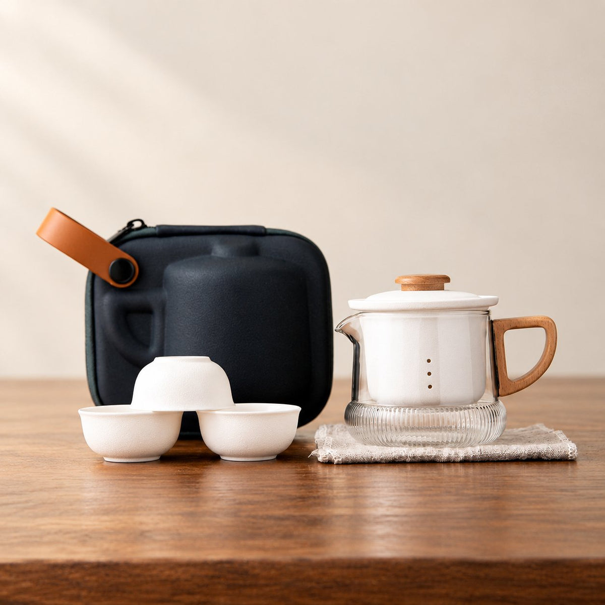 Ceramic infuser glass tea set with a ribbed glass brewer, wood handle, ceramic lid, removable ceramic infuser, and three small matching cups.