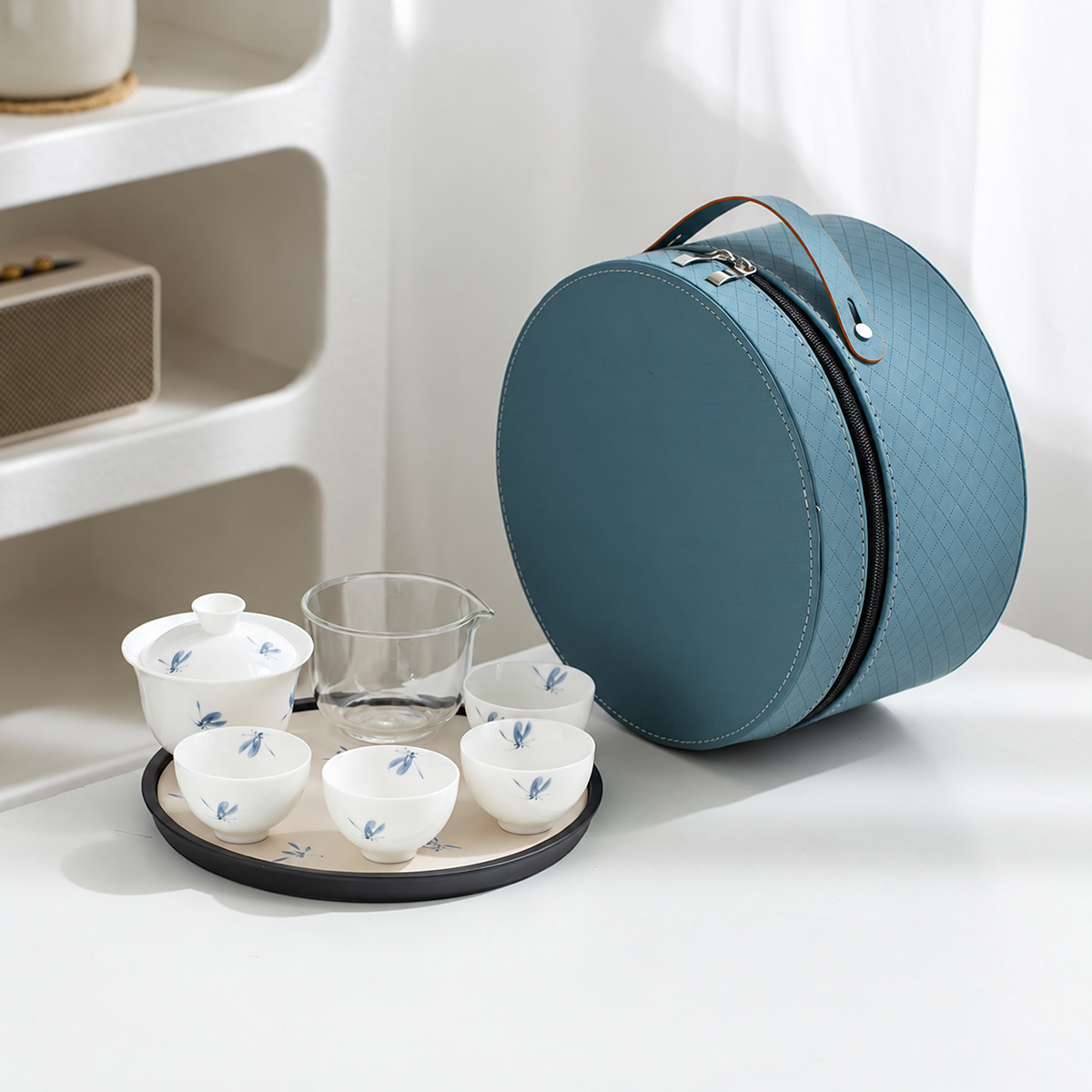 Gaiwan travel tea set with four cups arranged on its round tray beside the open zippered round carrying case.