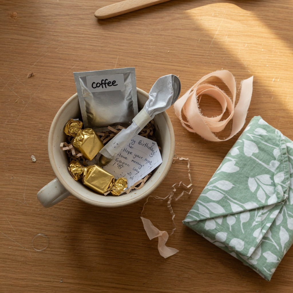 What to put in a coffee mug as a birthday gift, including sealed coffee, chocolate, tissue paper, and a handwritten note