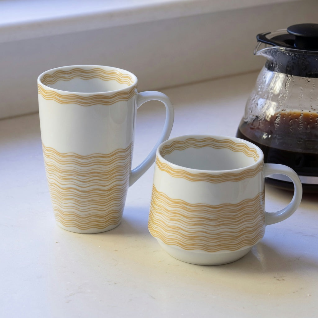 white and gold coffee mug comparison showing the taller waves mug beside the lower Kio mug on a kitchen counter
