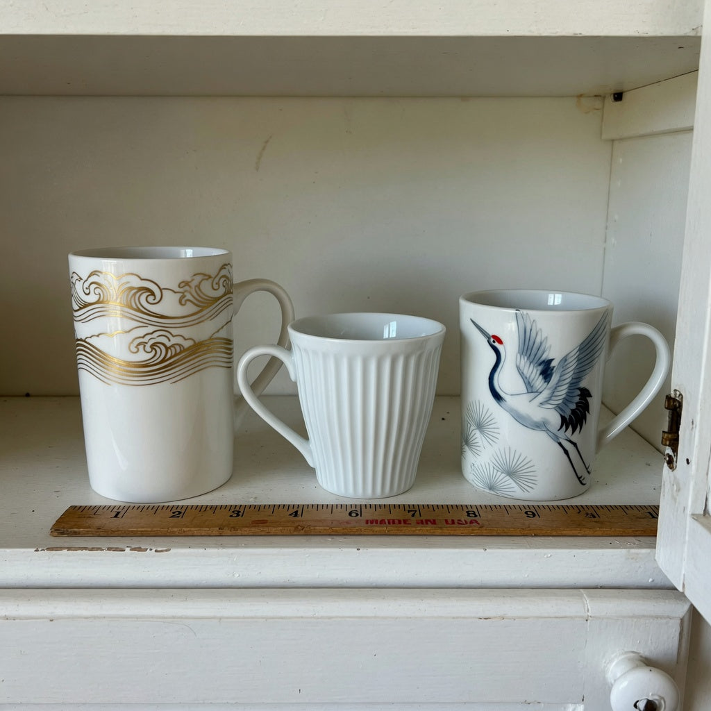 White pottery coffee mugs storage fit guide with tall waves, pleated, and crane mugs measured on a cabinet shelf