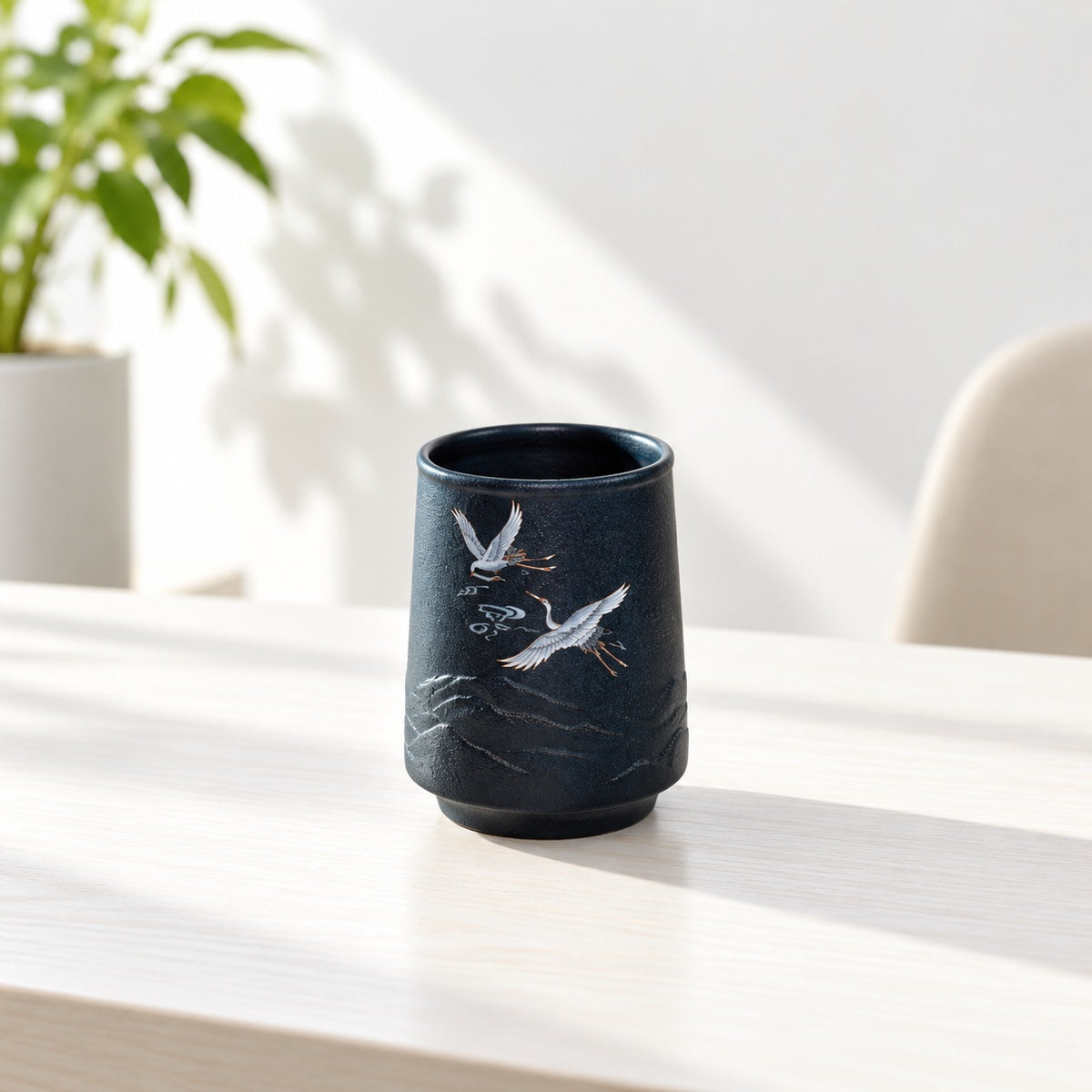Deep blue stoneware crane mug on a bright minimalist desk