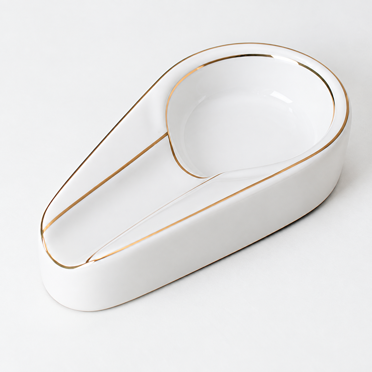 Close view of the empty white ceramic ashtray channel, round well and thin gold-colored edging