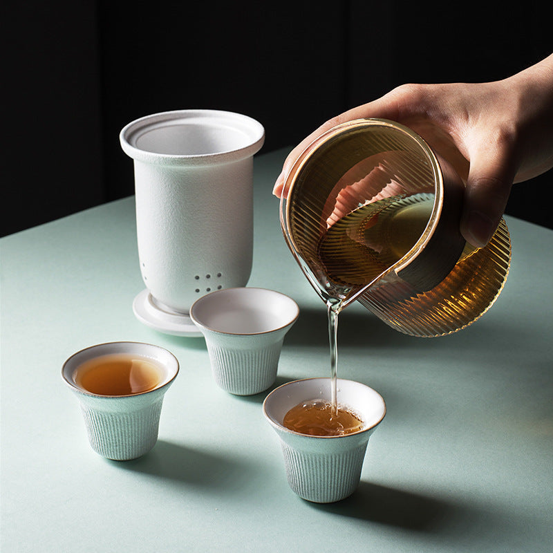 White ceramic tea set with three cups and glass pitcher pouring tea