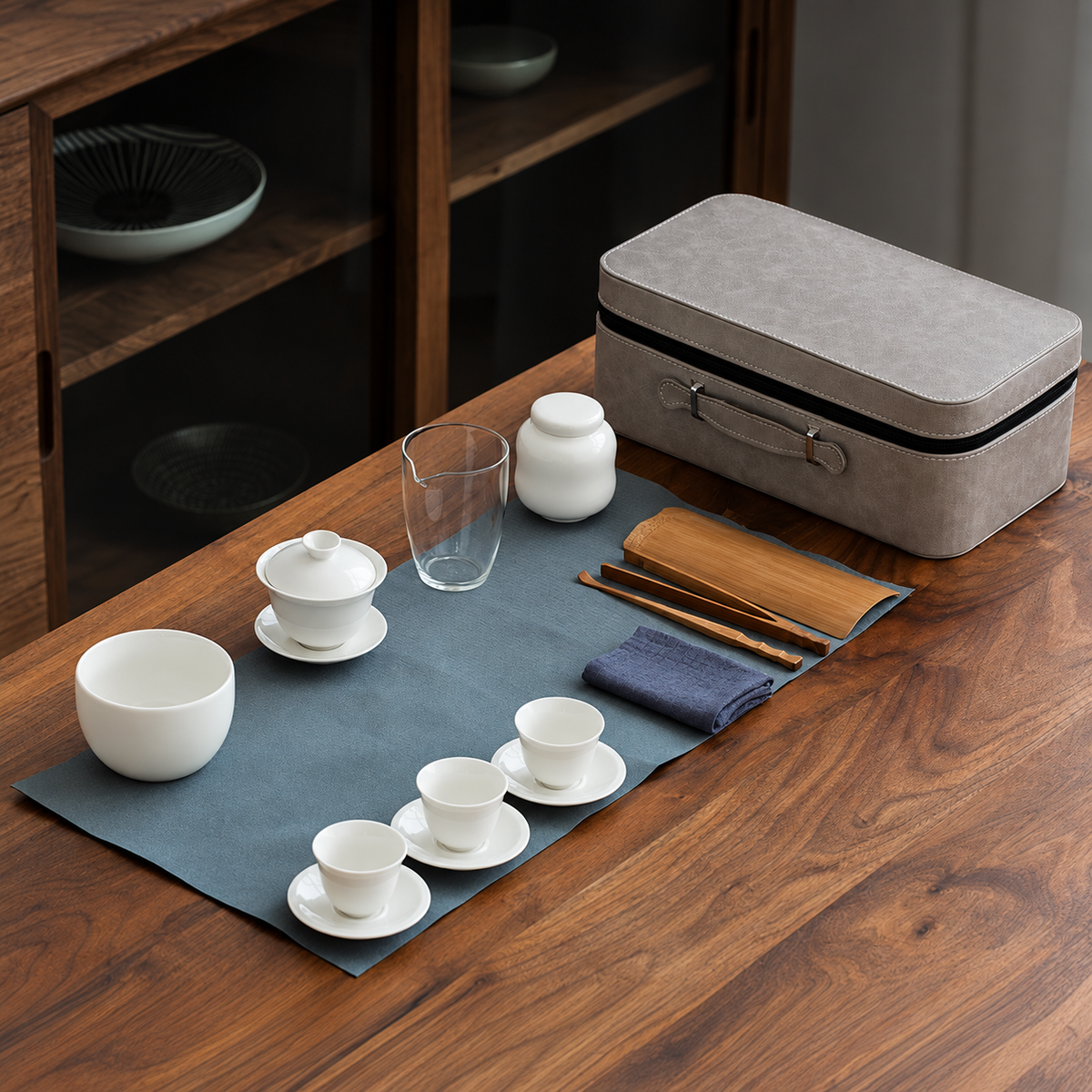 White porcelain gongfu tea set with three cups, saucers, glass pitcher and gray carry case