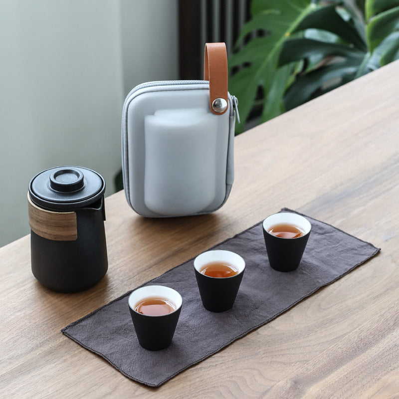 Black ceramic travel tea set with three cups, lidded pitcher and carry case
