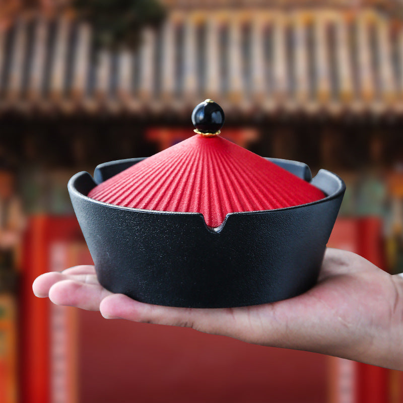 Red and black ceramic ashtray held in one hand
