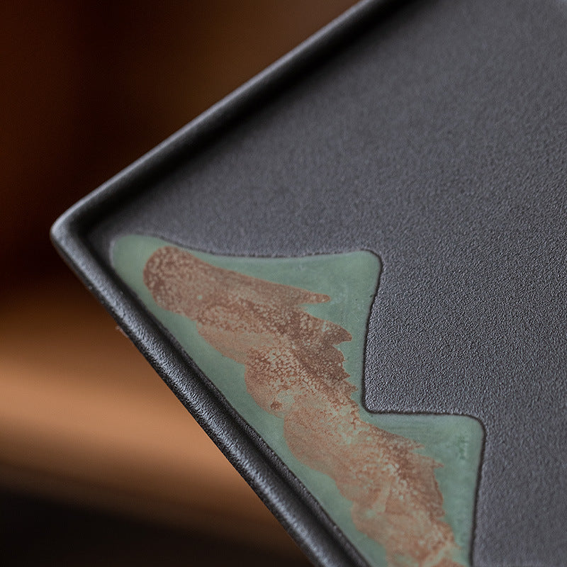 Close view of the mountain motif and textured black surface of the tea tray