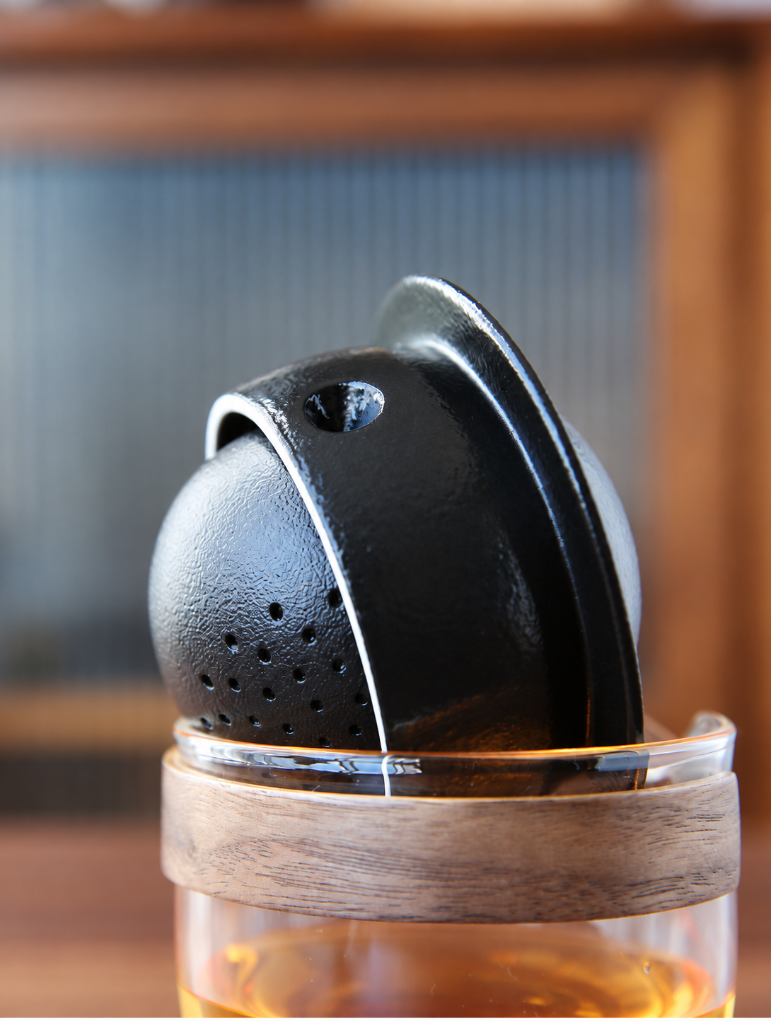 Close view of the black ceramic pivoting infuser inside the glass server with wooden grip
