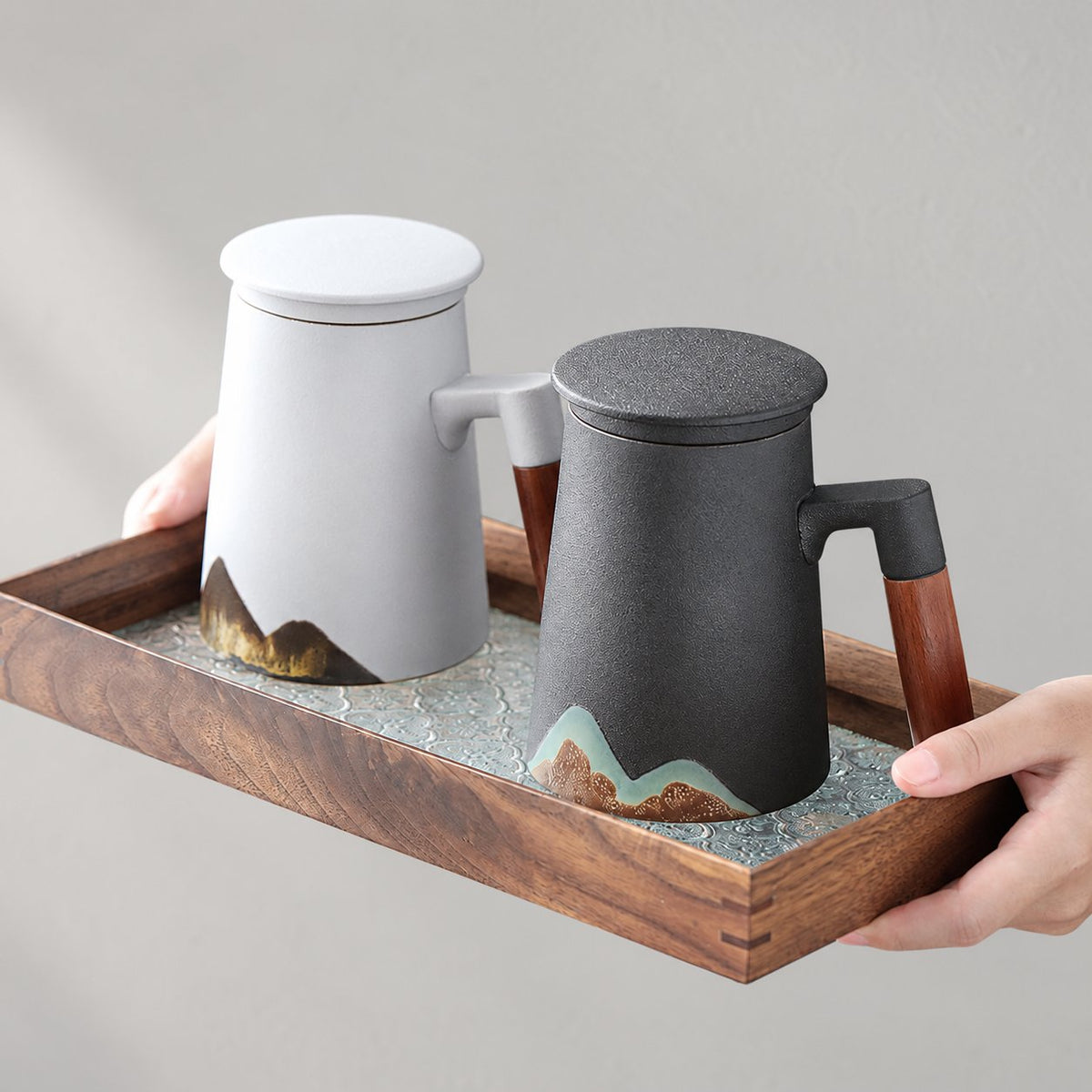 Black and white mountain mugs with lids on a wooden tray