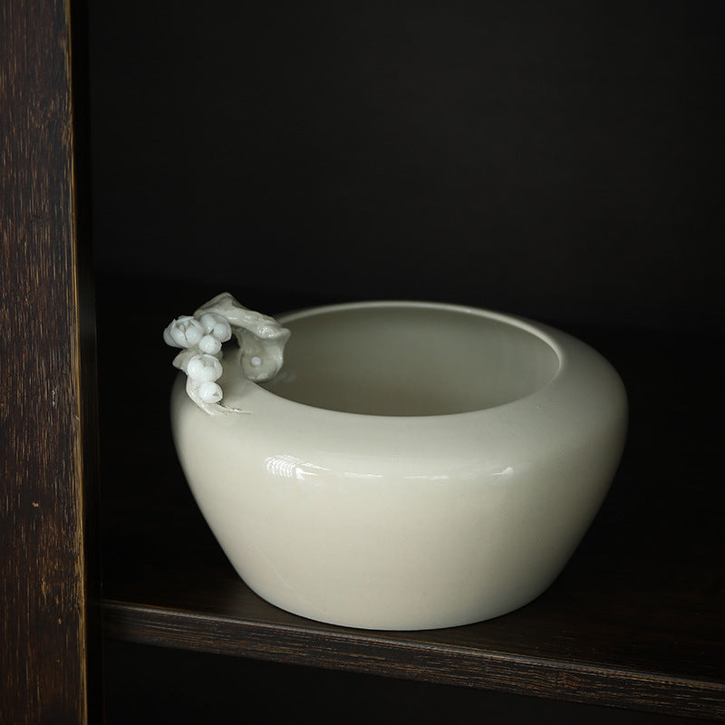 Plum blossom ceramic tea rinse bowl on a dark wooden shelf