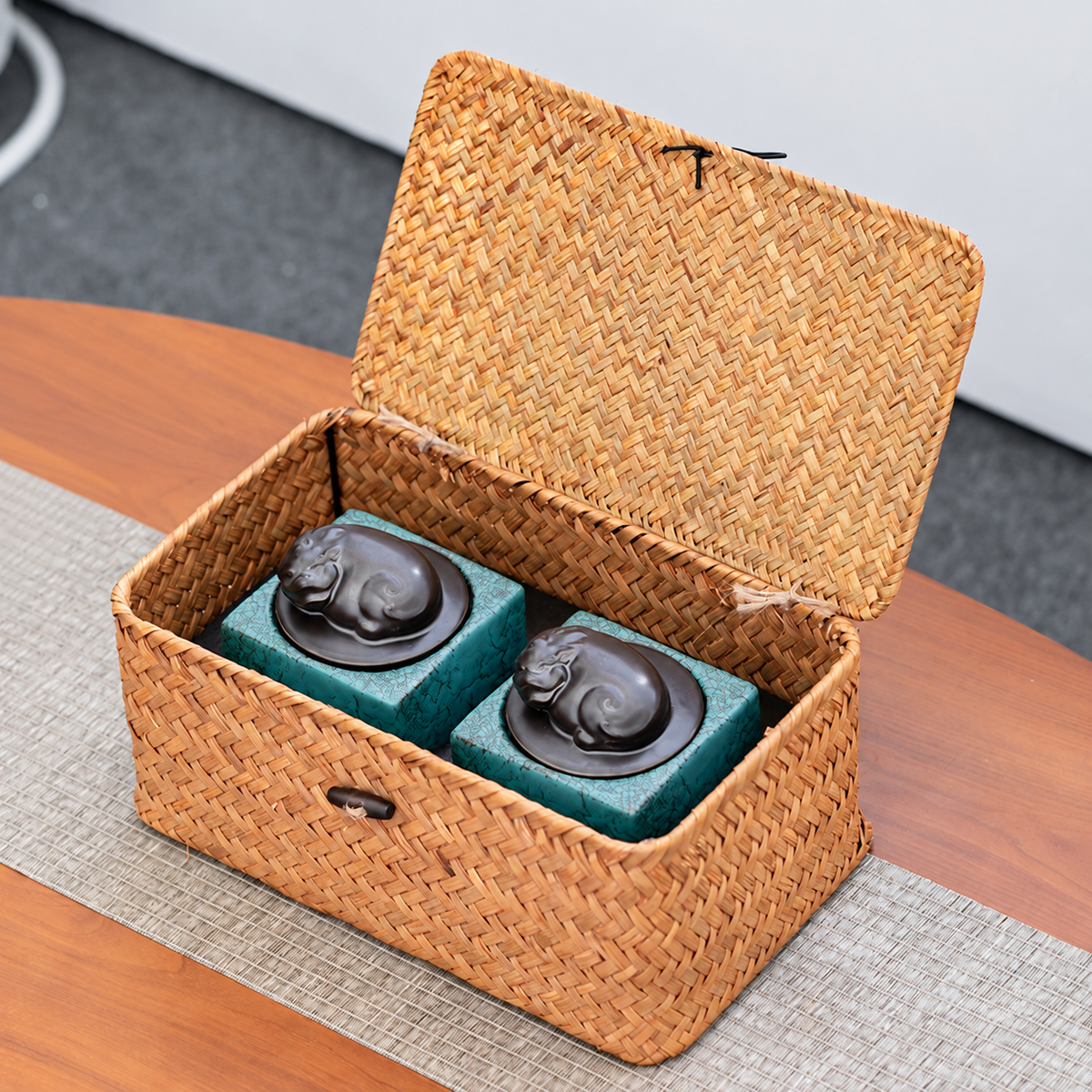 Two turquoise Pixiu-lid tea canisters nestled inside the open fitted woven basket