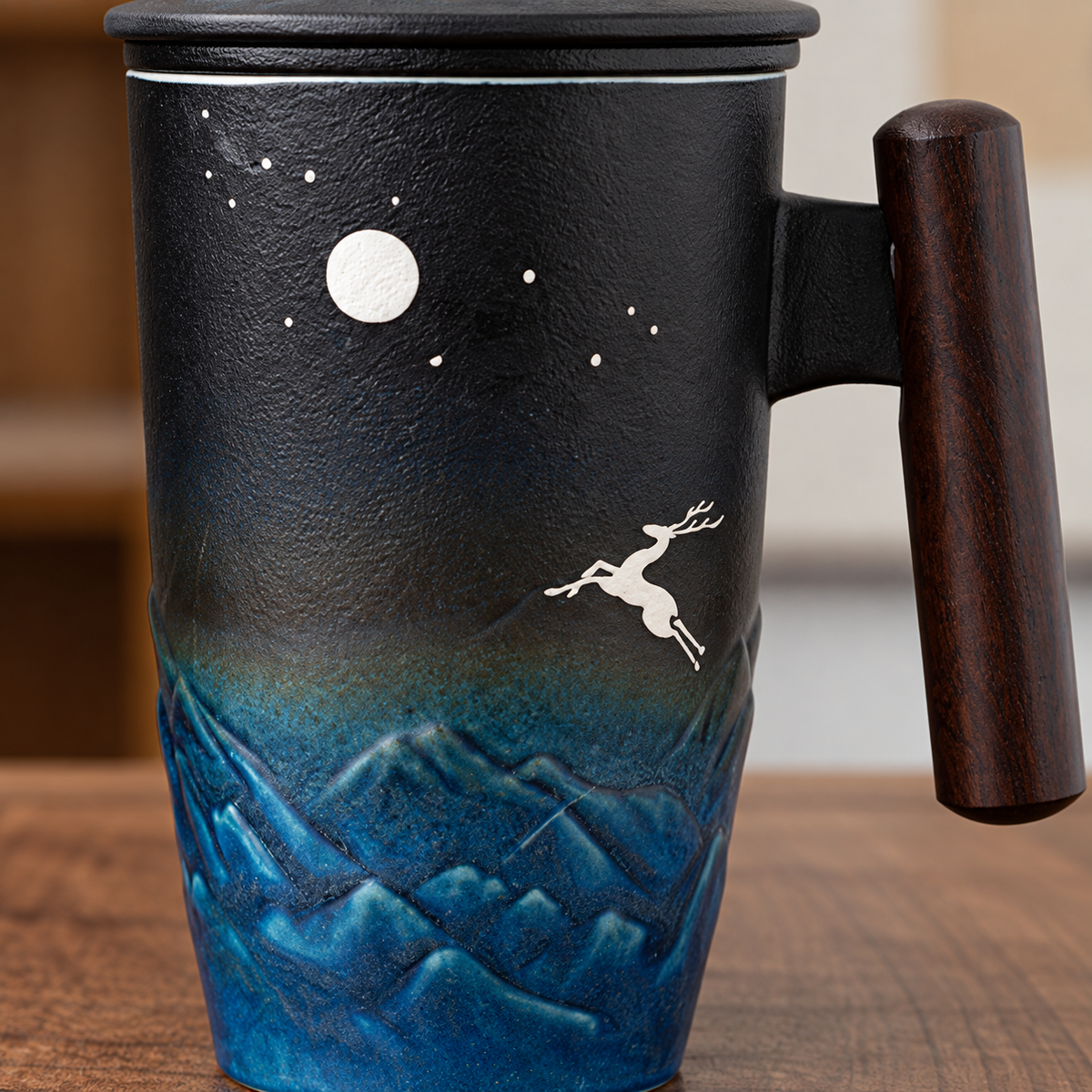 Close-up of the tall blue mug showing the wooden handle, deer and moon motif and raised mountain relief