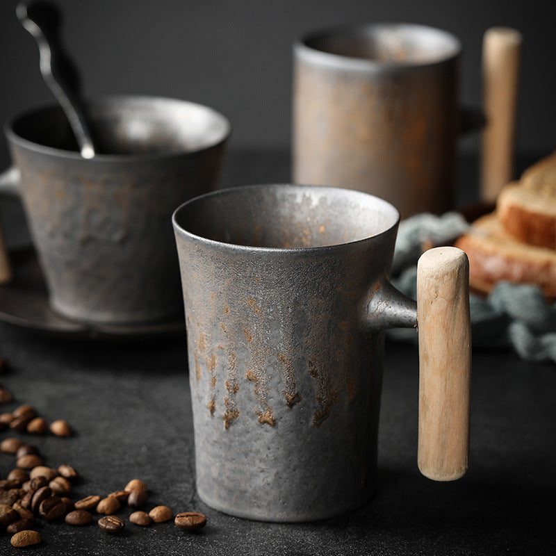 Textured ceramic coffee mugs with wooden handles on a dark table