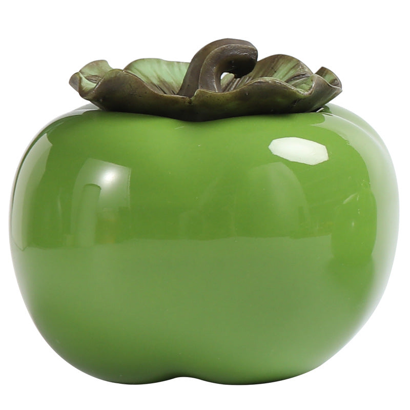 Green persimmon-shaped ceramic tea canister with a leafy lid