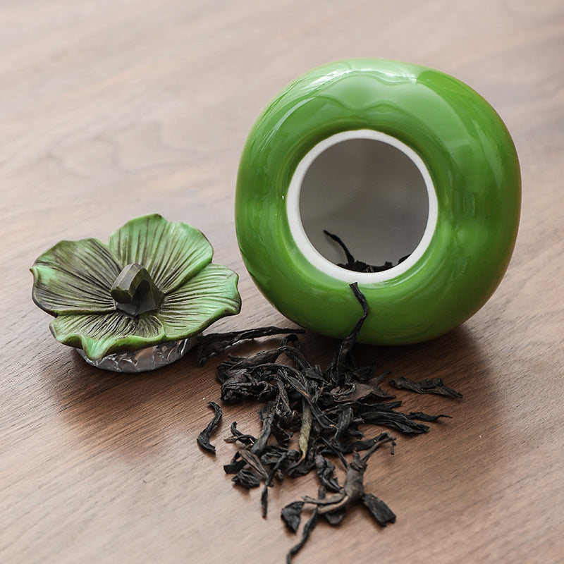 Open green ceramic tea canister showing the interior and removable lid