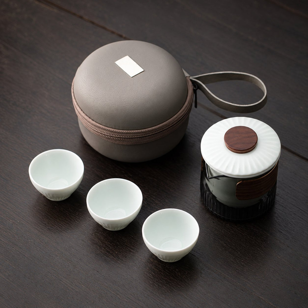 Ribbed glass travel tea pitcher with three white cups and a round carry case