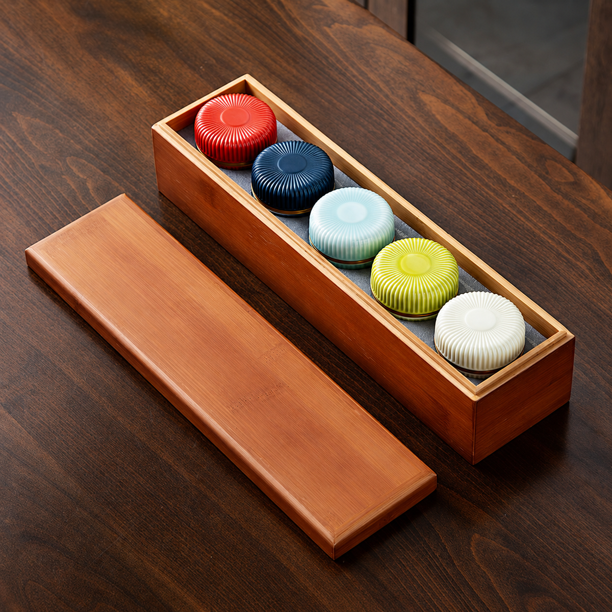 Five small ribbed ceramic tea jars in five colors with a fitted bamboo box and detached lid