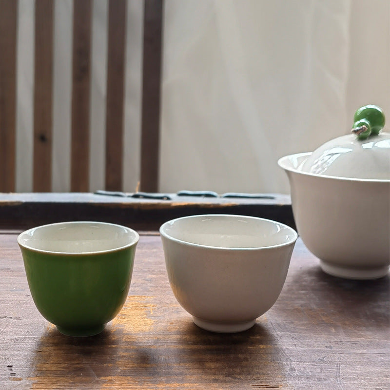 Green and ivory cups beside the matching lidded tea brewer