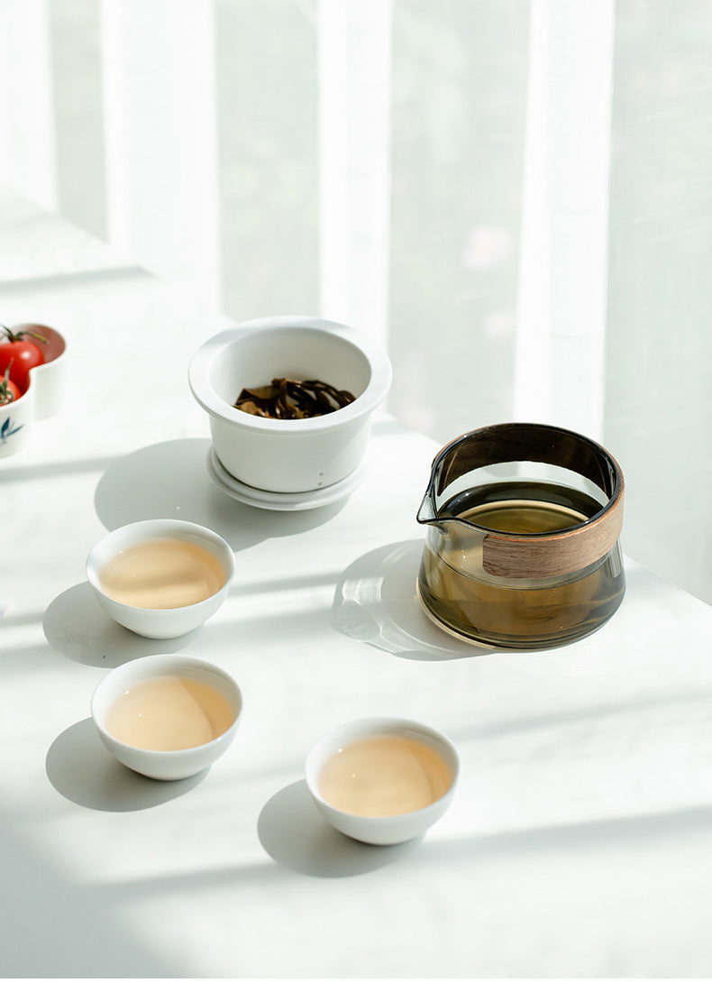 White travel brewer with the ceramic infuser removed, three cups and matching lid