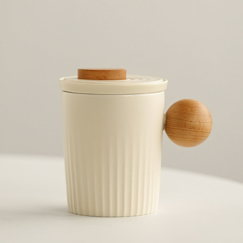 Cream ceramic tea infuser mug with a round wood-look handle and lid