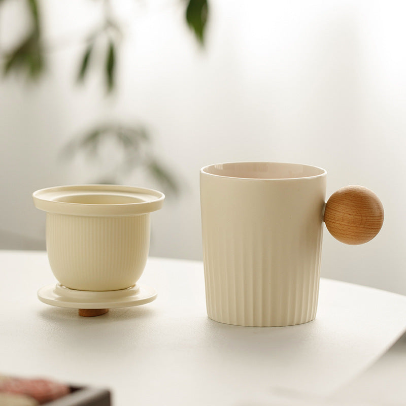 Cream ceramic mug beside its removable infuser and lid