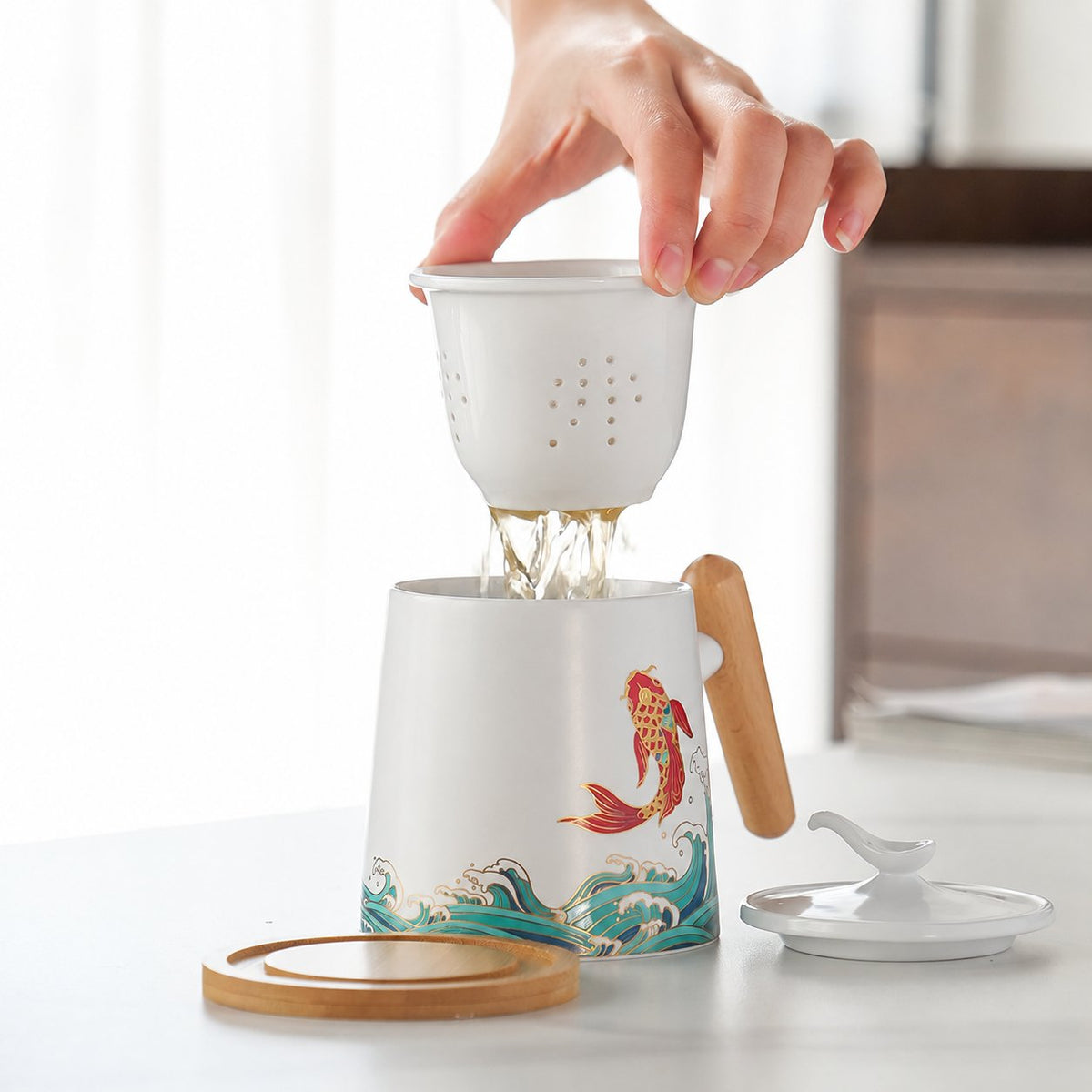 Ceramic infuser lifted above the koi tea mug