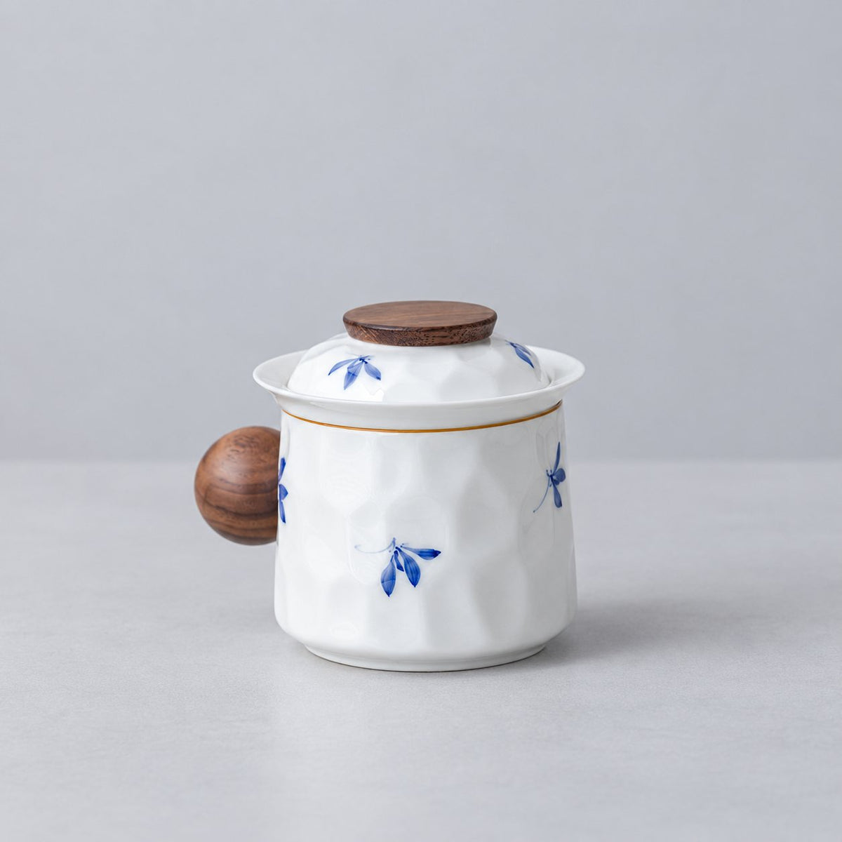 White porcelain infuser mug with blue floral motifs, round wood handle and fitted lid