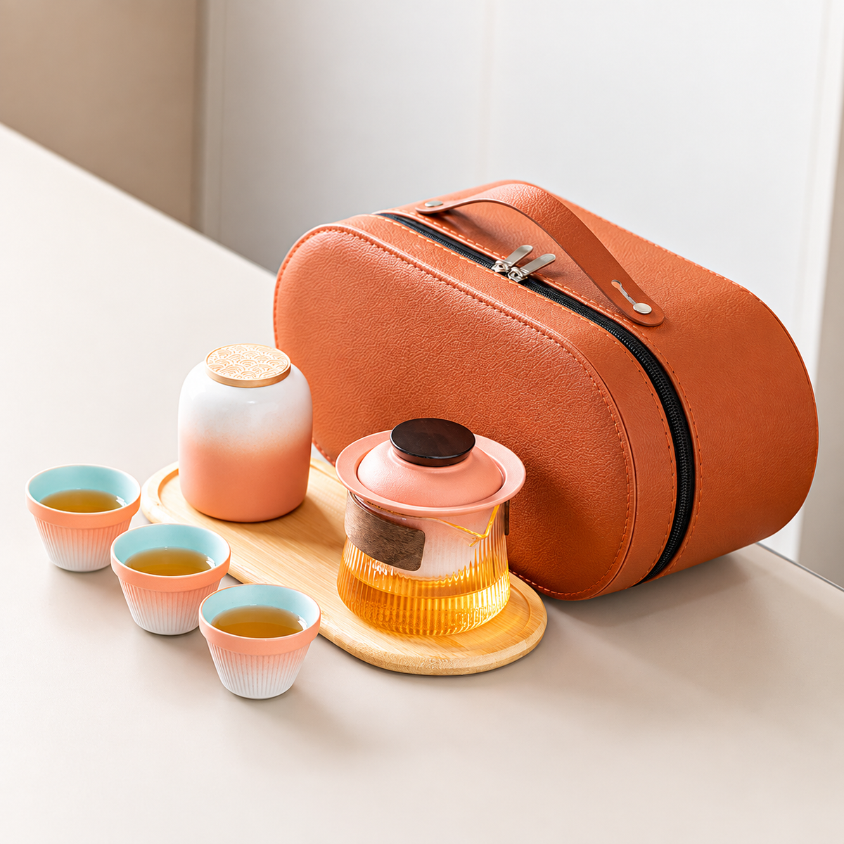 Pink gradient travel tea set with a wood-grip glass brewer, three cups, jar, tray and orange case