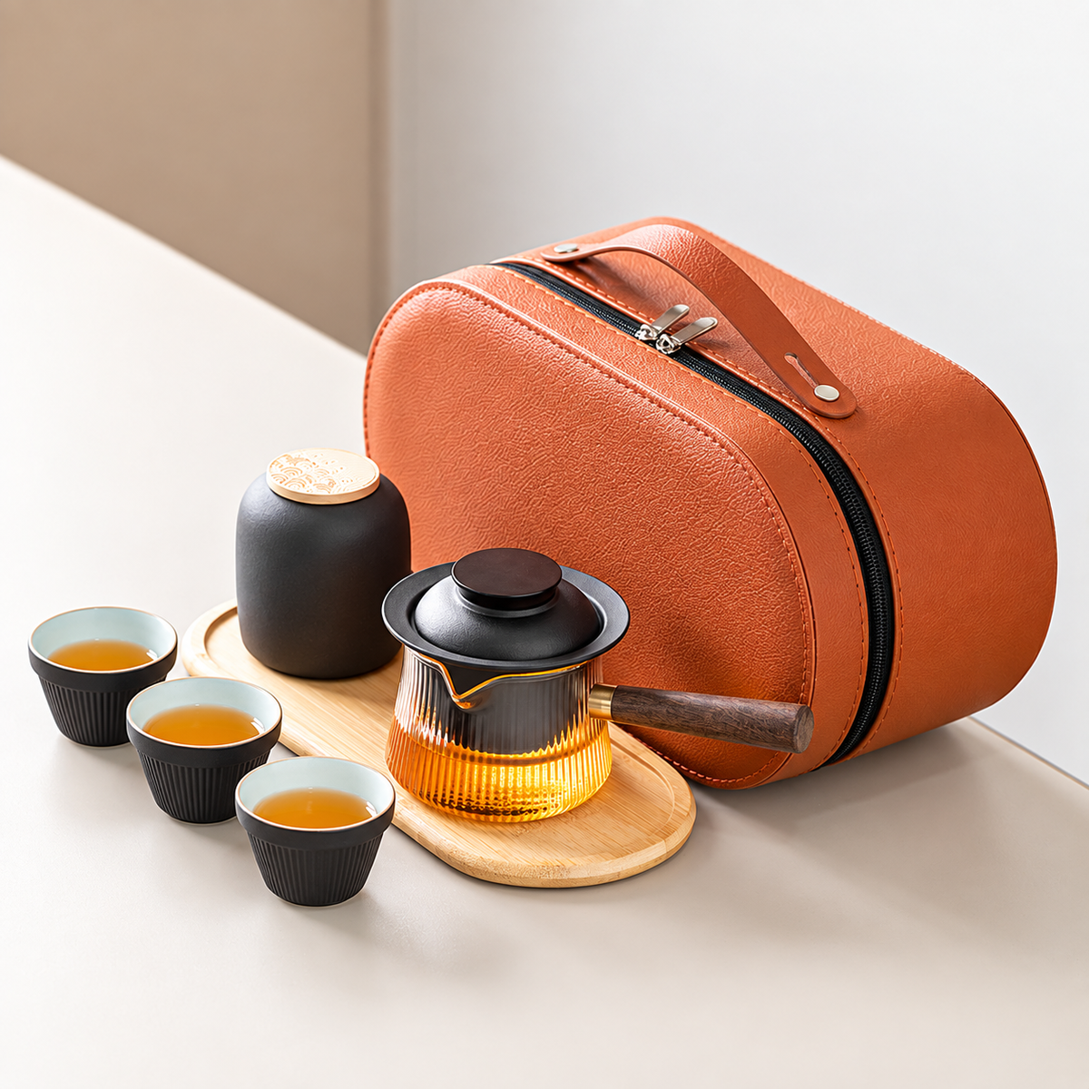 Black travel tea set with a side-handle glass brewer, three cups, jar, tray and orange case