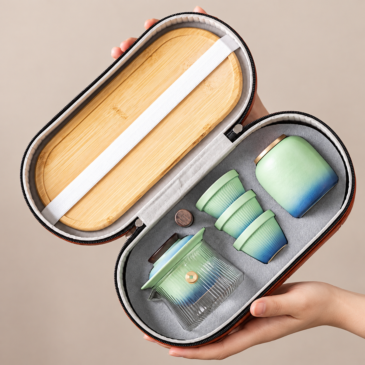 Open orange carrying case holding the nested glass and ceramic travel tea set