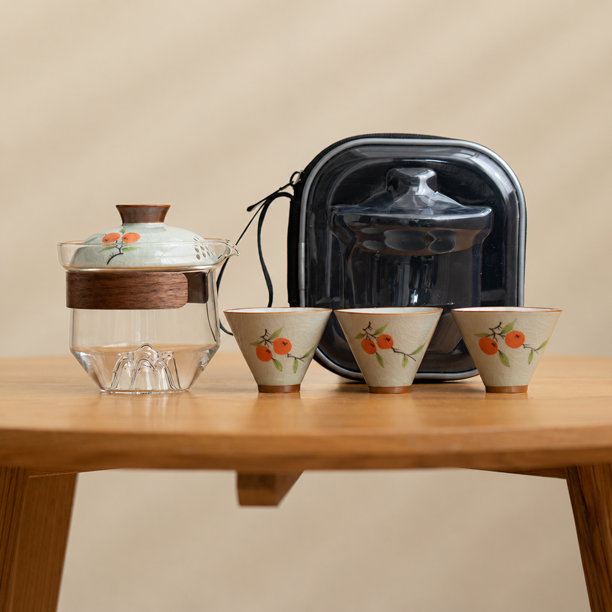 Persimmon / Clear glass tea brewer with three patterned ceramic cups and a black travel case
