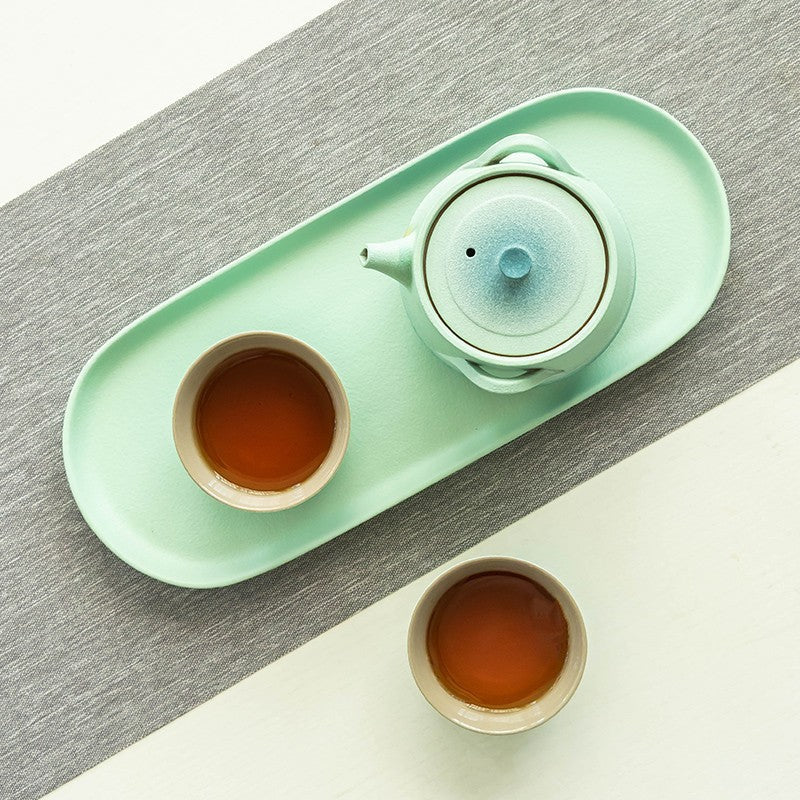 Overhead view of the blue-gradient teapot, lid and cup interiors on an oval tray