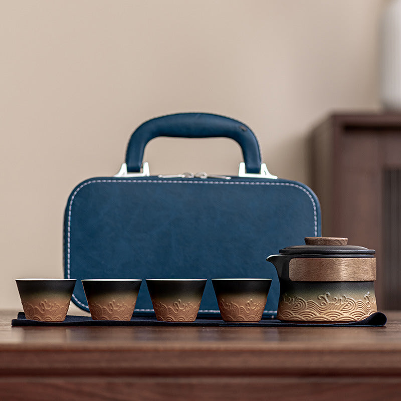 Black and ochre wave-relief ceramic brewer with four cups and blue carrying case