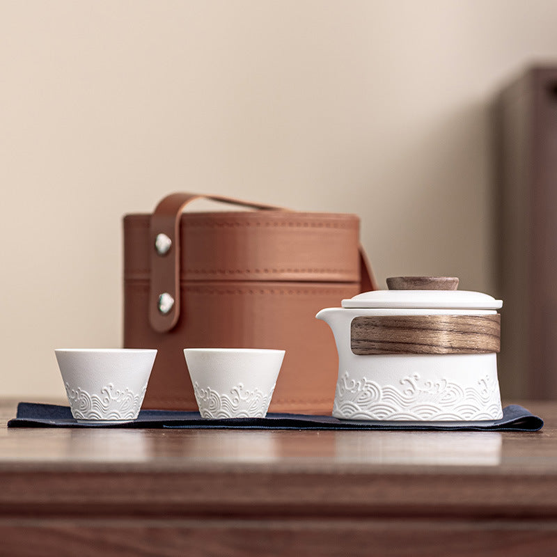 White wave-relief tea brewer with two cups, cloth and brown handled case