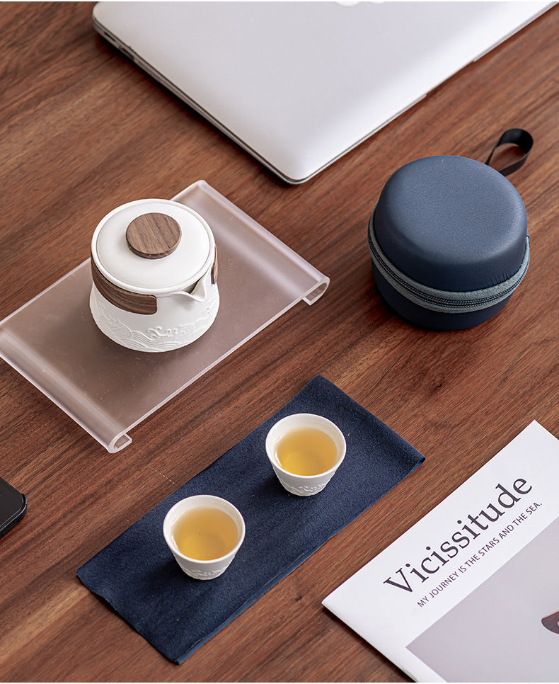 White wave-relief tea set with two cups of tea and its navy zip case on a desk