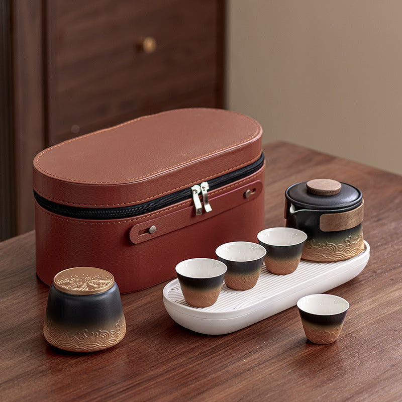 Black and amber wave-relief tea brewer with four cups, canister, oval tray and fitted case