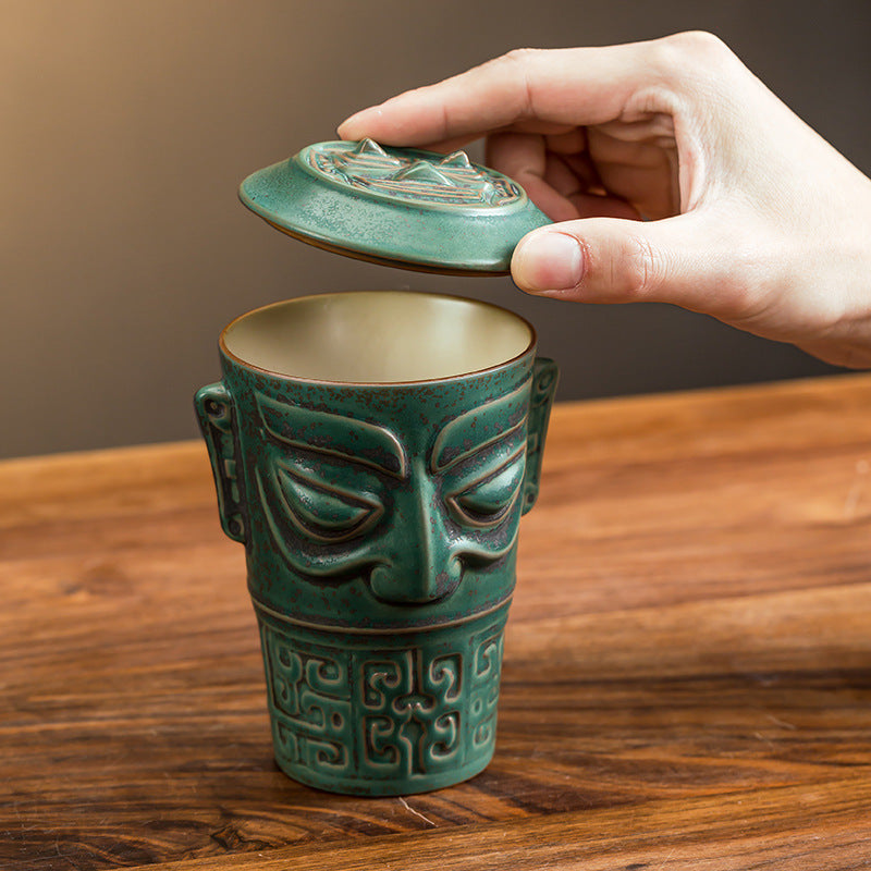 Lifting the lid from a green mask ceramic tea cup
