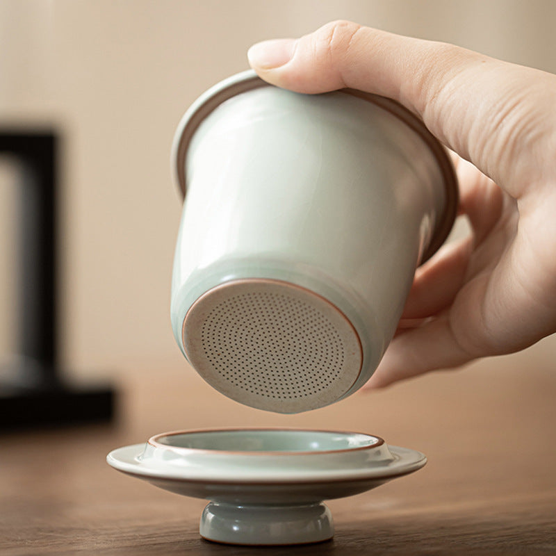 Hand showing the fine perforations in the removable ceramic tea infuser above the lid
