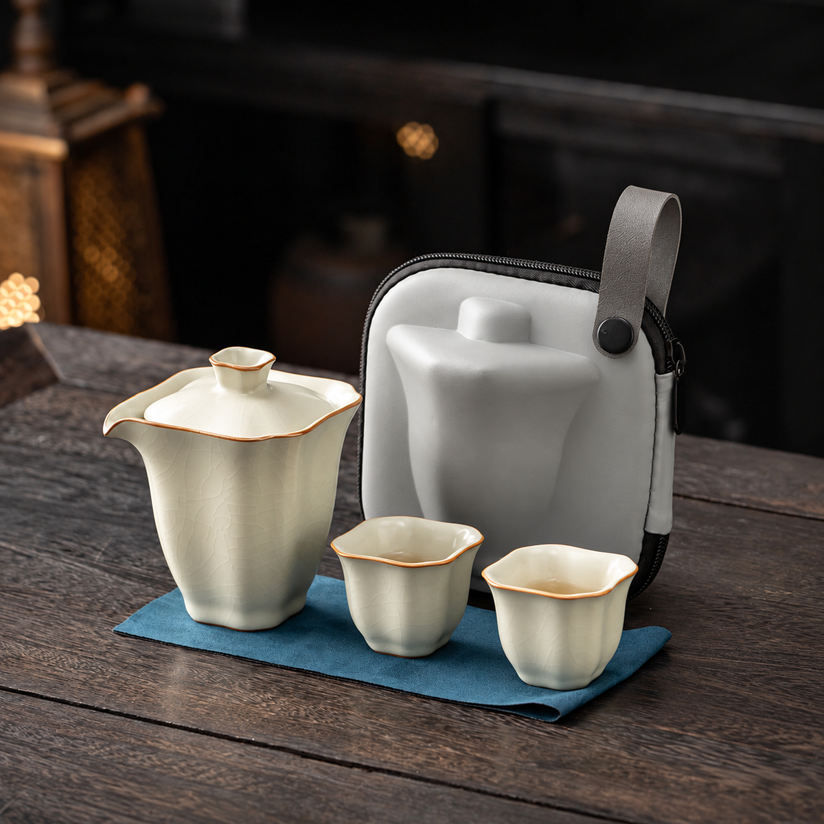Cream crackle-glazed square travel brewer with two cups, blue cloth and gray carrying case