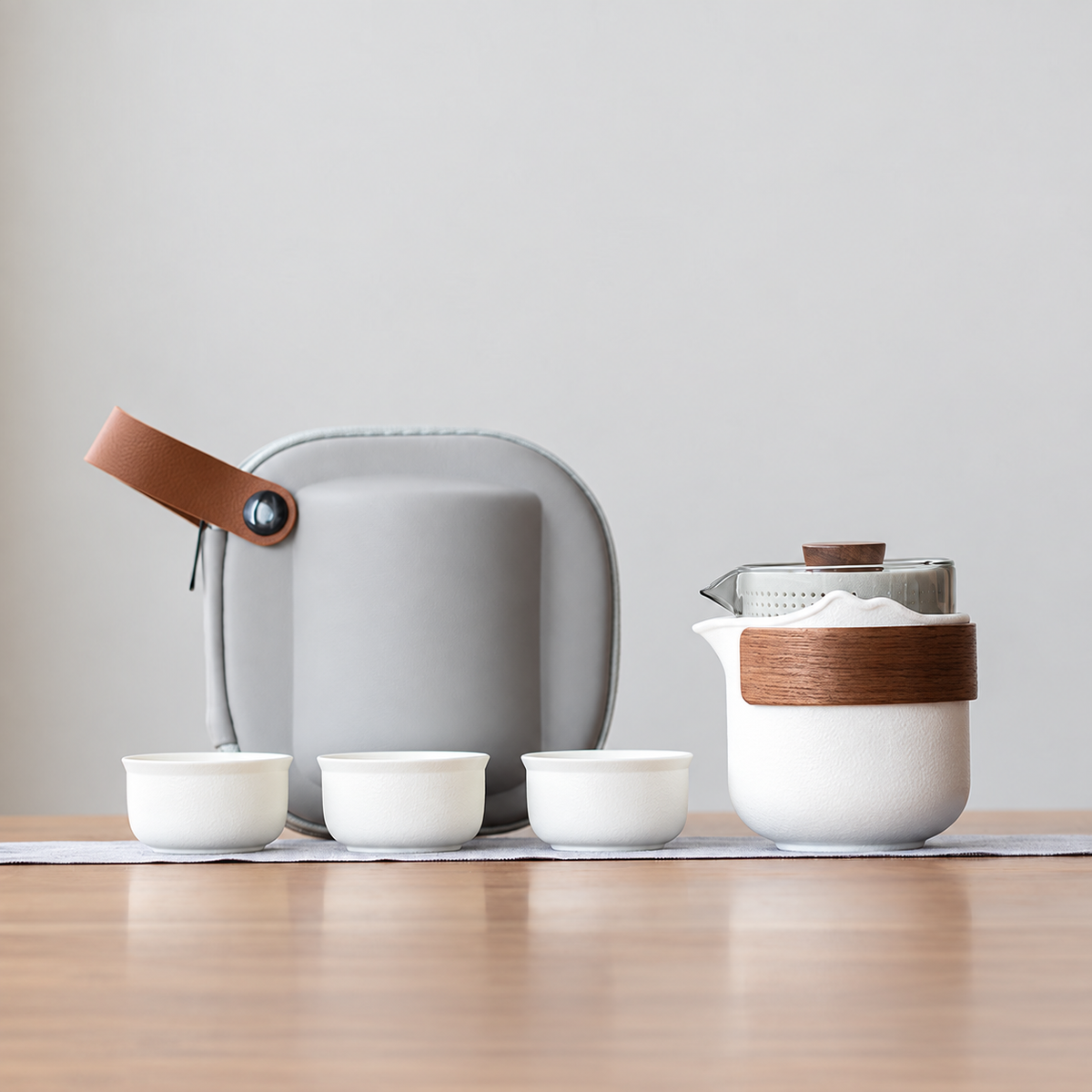 White nested glass and ceramic travel tea set, bamboo wrap configuration, with three cups and gray case