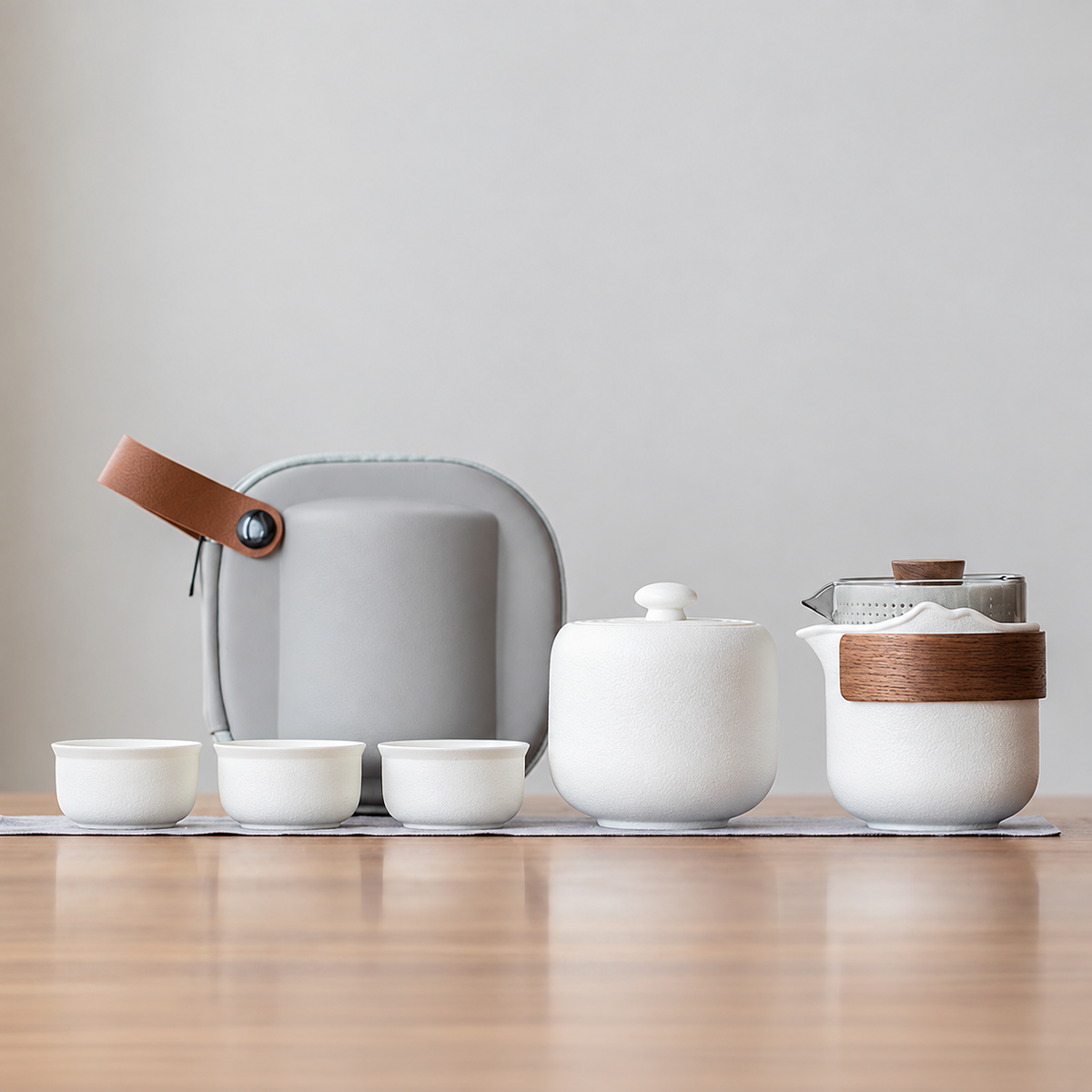 White nested glass and ceramic travel tea set, bamboo wrap and tea jar configuration, with three cups and gray case