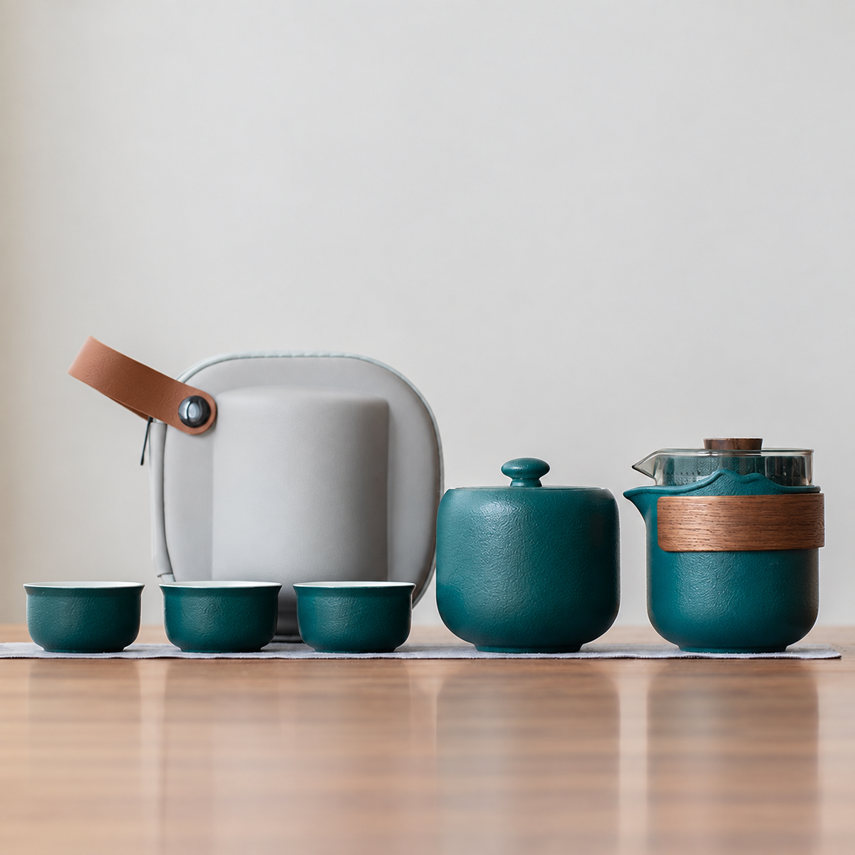 Green nested glass and ceramic travel tea set, bamboo wrap and tea jar configuration, with three cups and gray case