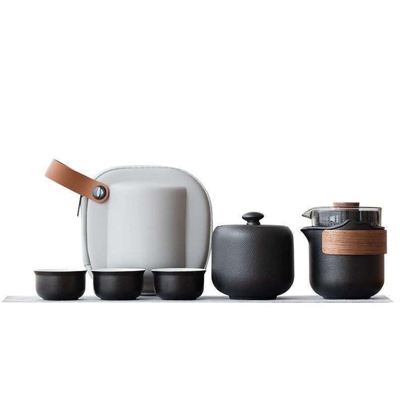 Black nested travel tea set with bamboo wrap, tea jar, three cups and gray case on a white background