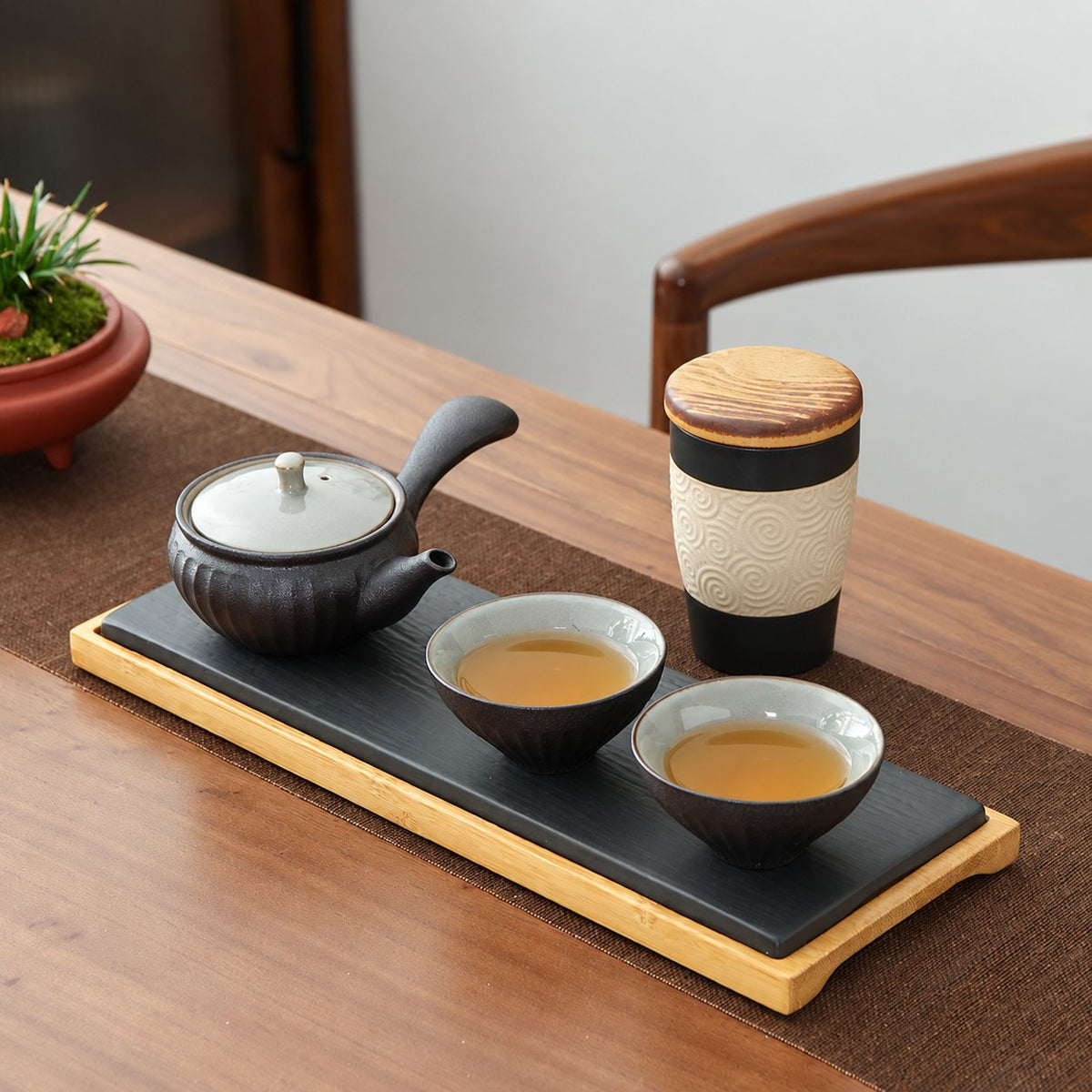 Charcoal ceramic tea set arranged for two on a wooden table