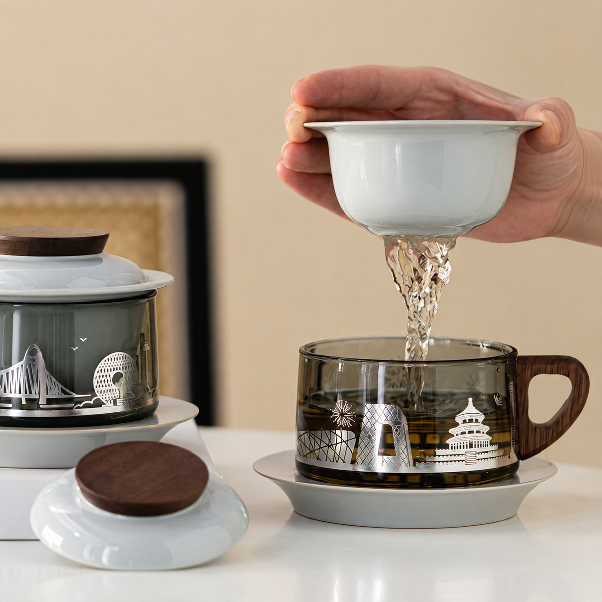 Hand lifting the ceramic infuser above the Beijing skyline glass mug as tea drains into the cup