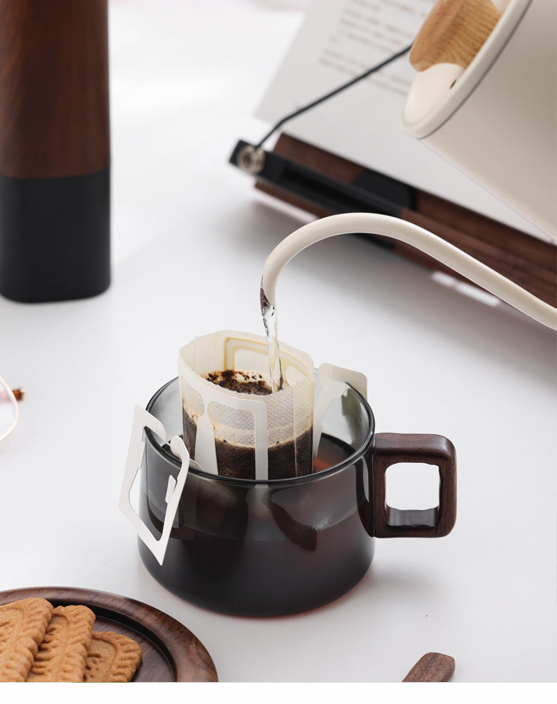 Coffee brewing through a paper filter suspended inside the smoked glass mug with square wooden handle